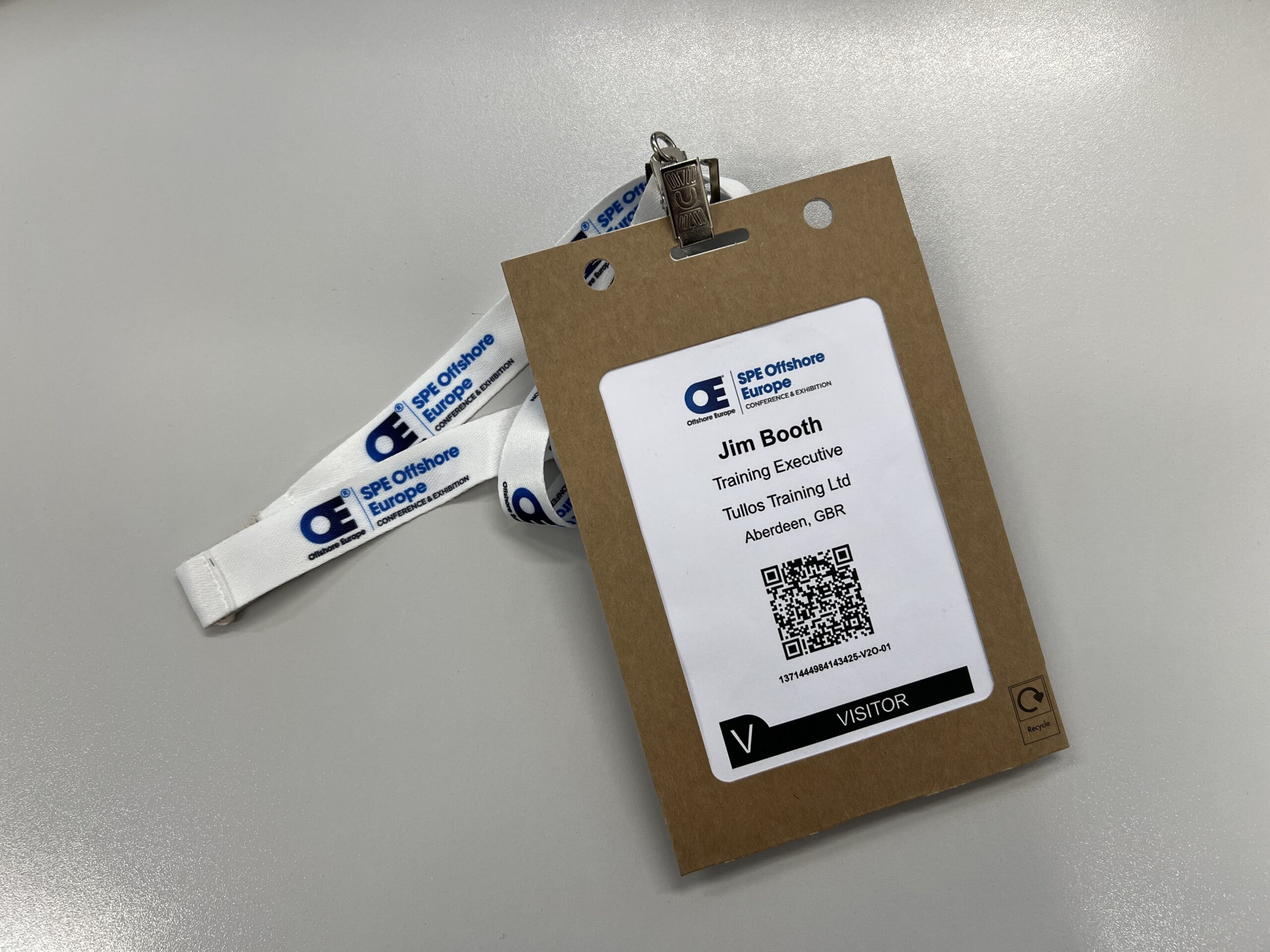 White lanyard with the blue SPE Offshore Europe logo on it.  Jim's entry pass is attached to the lanyard and within a brown cardboard casing.